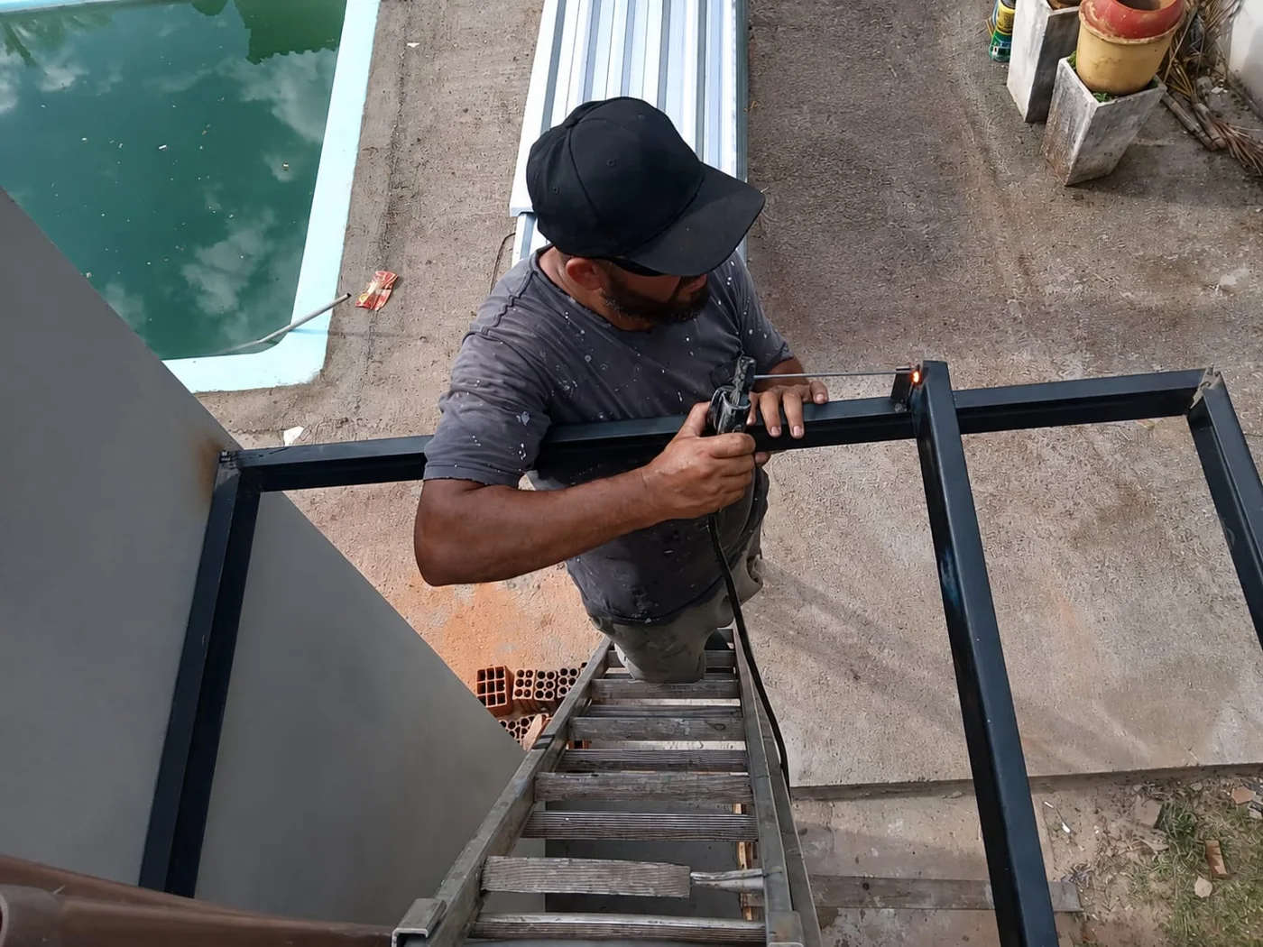 Profissional da Serralheria LC trabalhando manualmente na fabricação de uma estrutura metálica